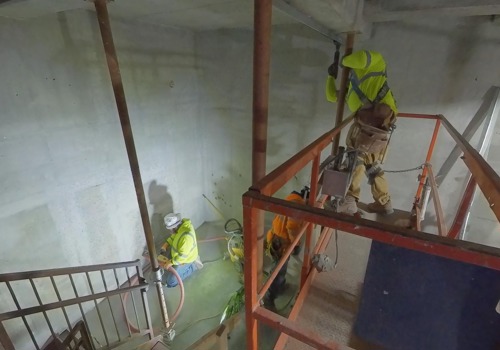 A group of carpenters install steel studs inside a high-rise building.