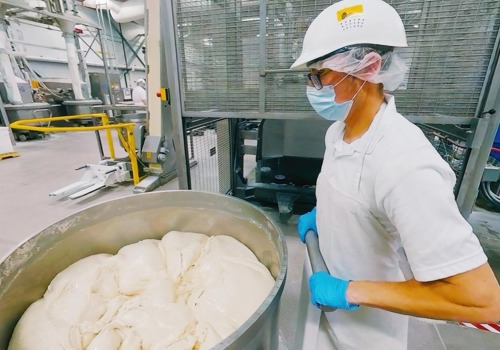 Dough is wheeled across the production floor by a baker.