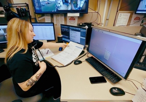 A 911 operator responds to an emergency call while referencing an emergency medical dispatch book.